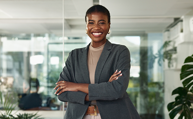 Smiling professional woman standing with arms crossed in a modern office