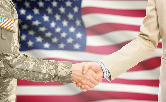 Handshake between a military service member and a civilian in front of an American flag