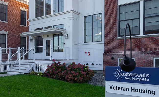 Exterior of an Easterseals New Hampshire veteran housing building with sign in the foreground